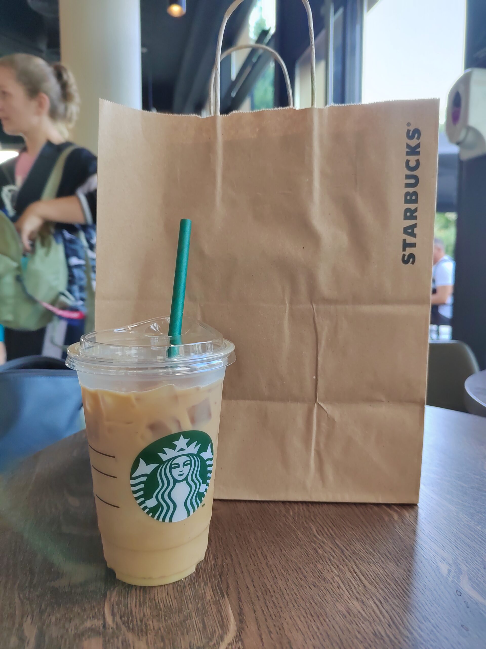 a starbucks brown sugar shaken espresso in front of a starbucks paperbag on a table